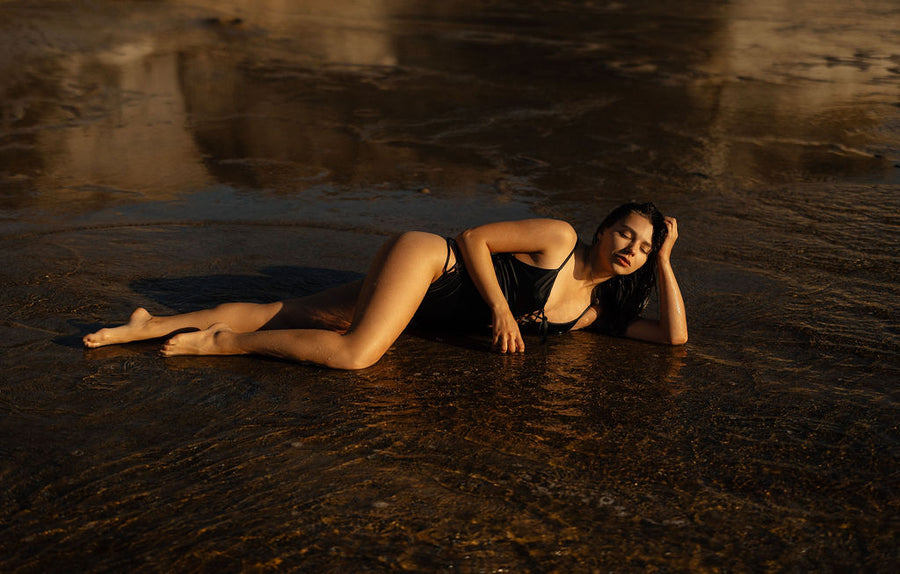 Woman lying in water at sunset with warm lighting